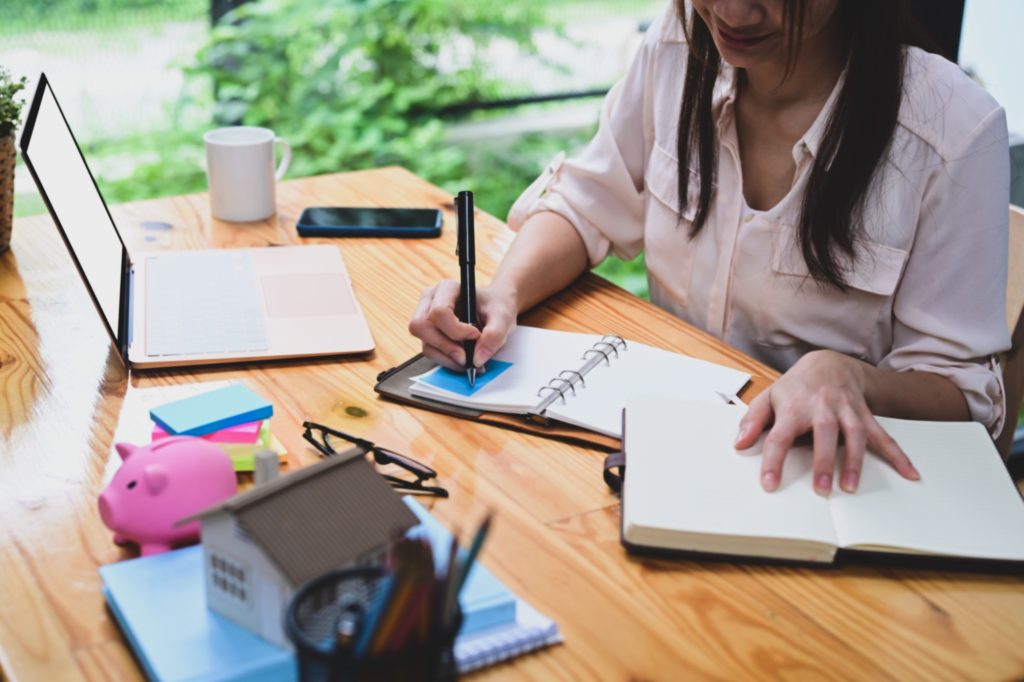 Businesswoman writing information on notebook at office desk.