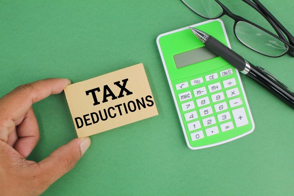 pen, calculator, glasses and paper with the word Tax Deductions.