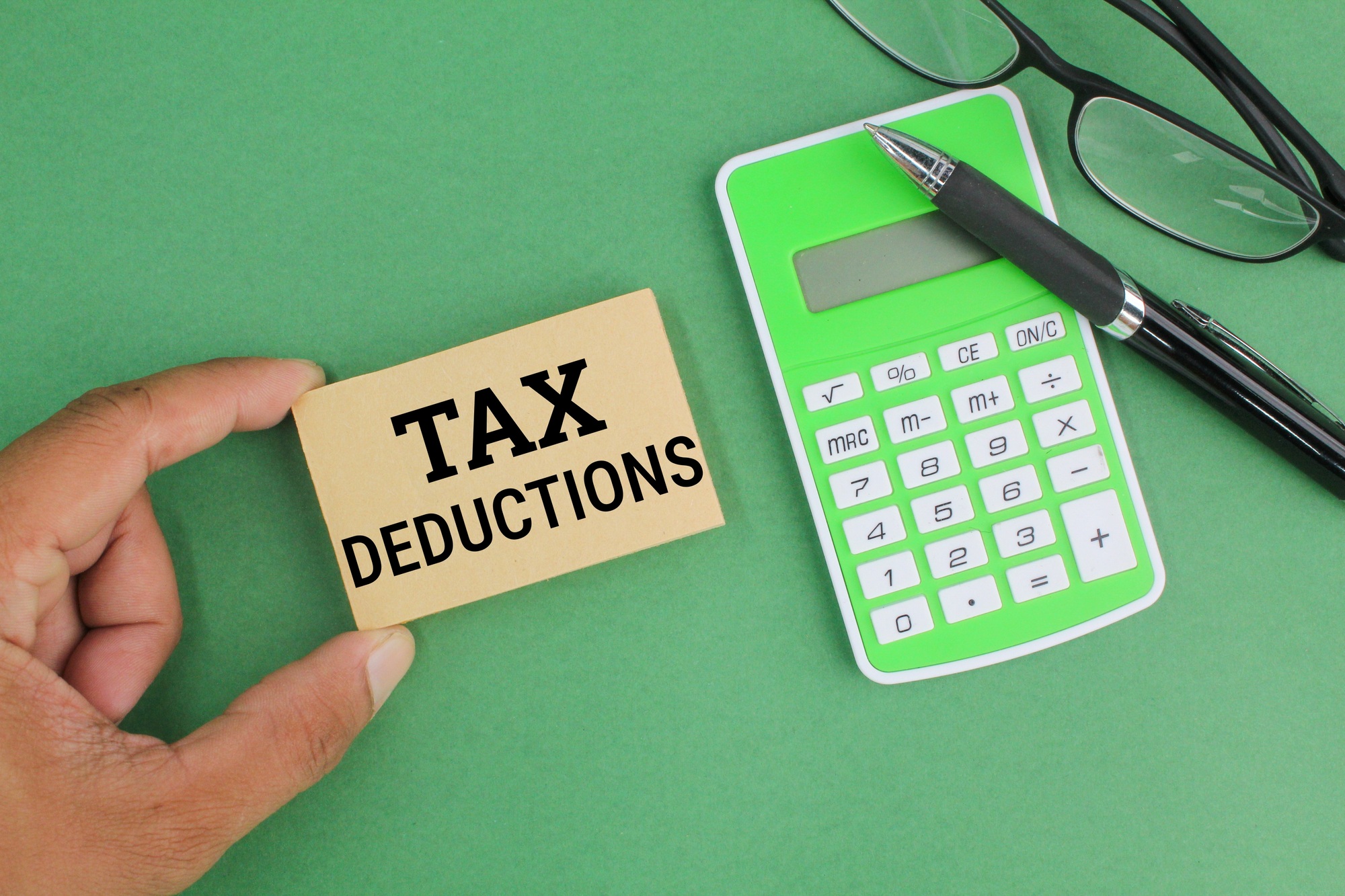 pen, calculator, glasses and paper with the word Tax Deductions.